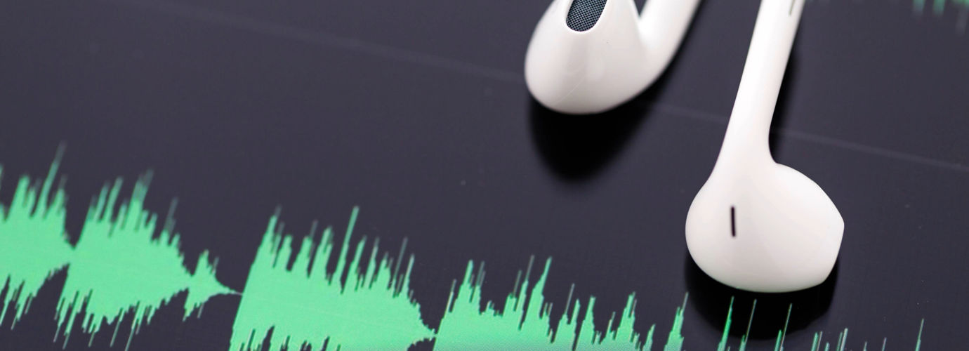Photo of earphones lying on a screen showing soundwaves.